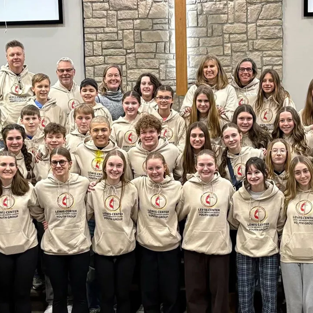 Church youth group wearing matching hoodies gathered together in sanctuary for group photo