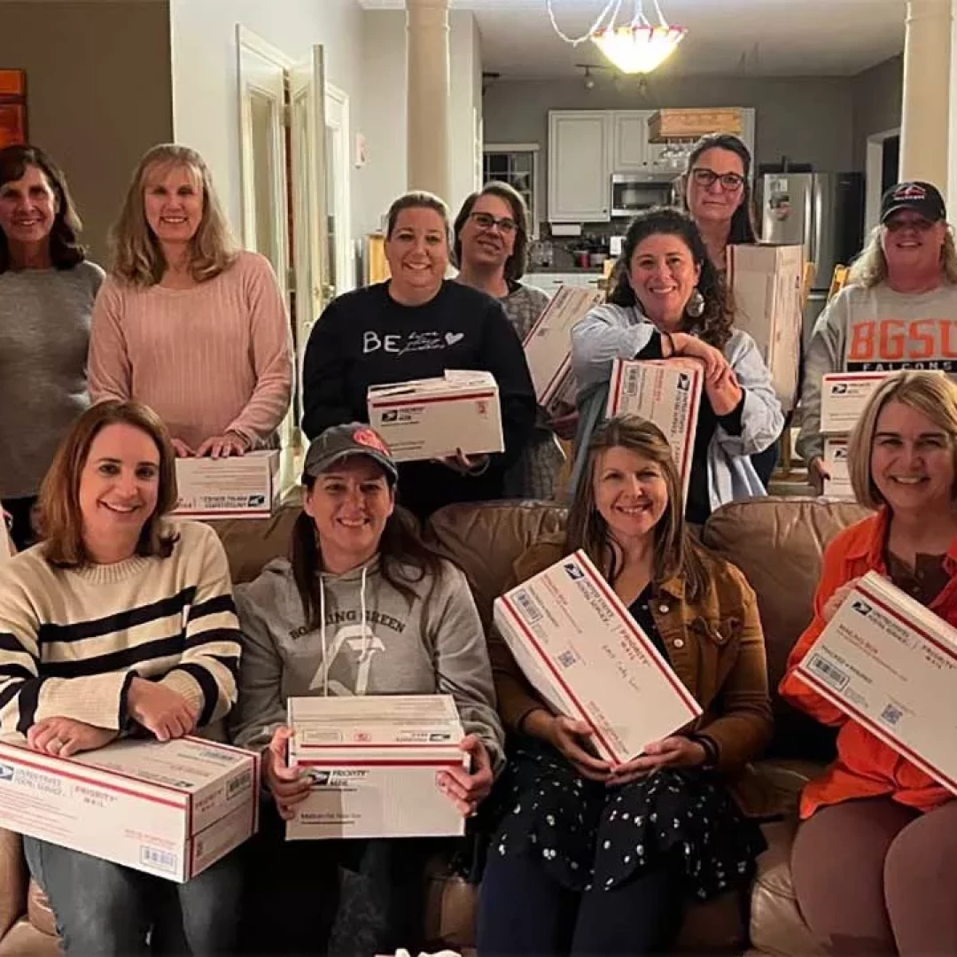 Group of women holding care packages and shipping boxes during community outreach gathering