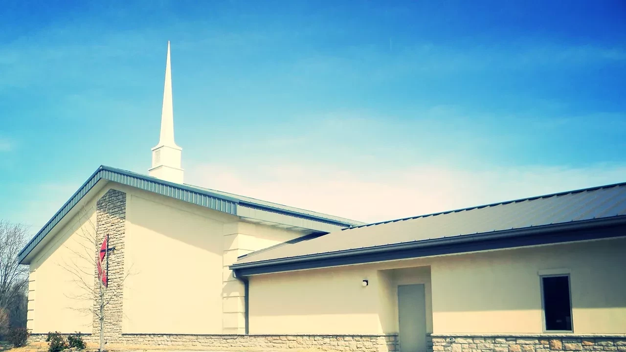 Church building exterior with steeple and clear blue sky