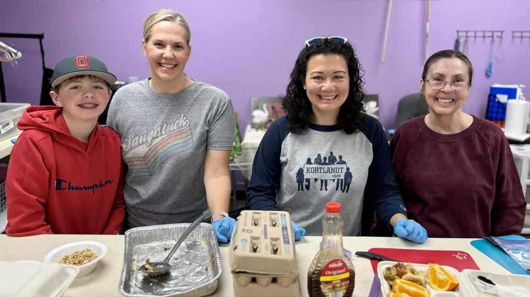 Volunteers preparing food together in kitchen during church community meal service
